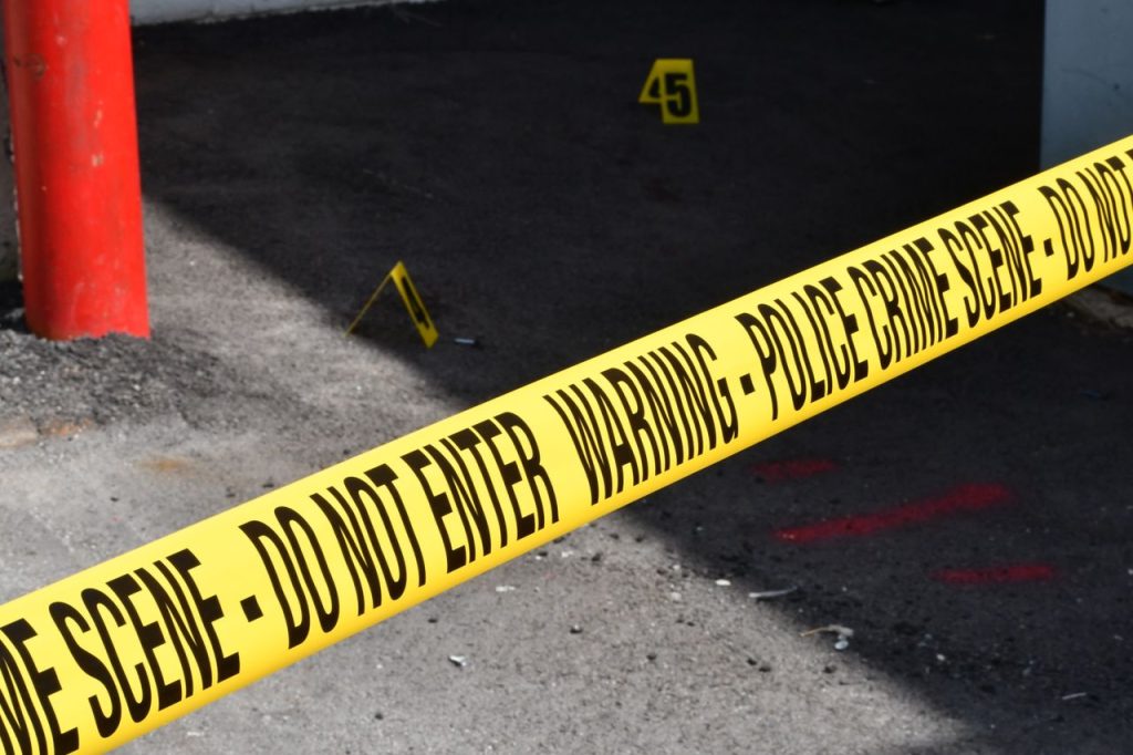 Yellow police crime scene tape marking a restricted urban area on concrete ground.